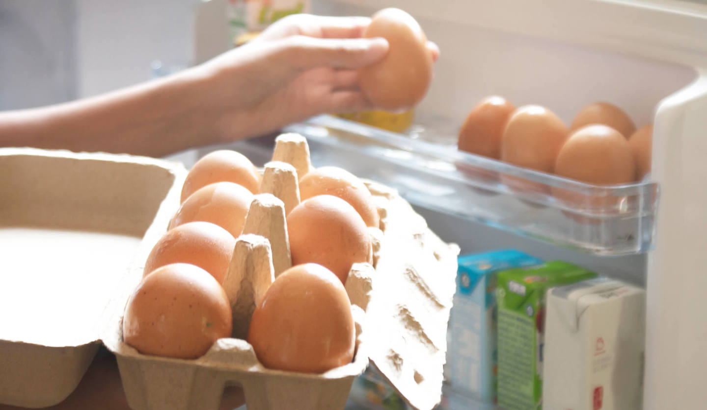 パックに入った卵を冷蔵庫のドアにある卵ケースへ移しかえている手元の様子