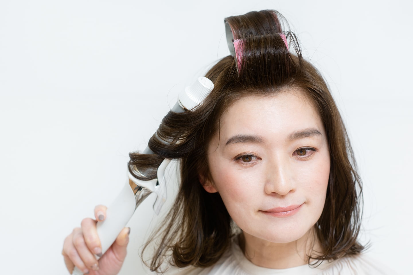 ヘアアイロンに、耳前の髪を中間から外向きに巻きつけて、リバースカールをつける。