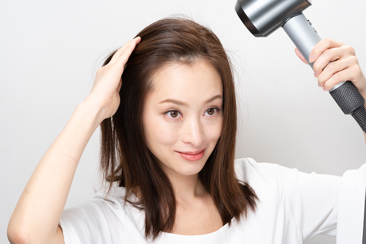 手ぐしで分け目と逆方向にとかしながらドライヤーをあて、前髪の立ち上がりをつくる。