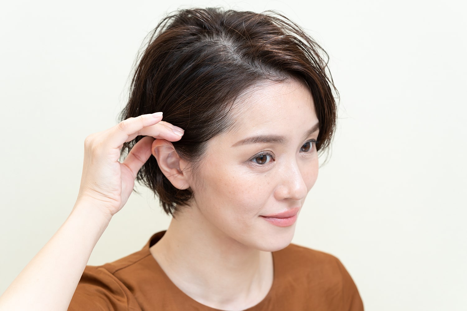 片側の髪だけ耳にかけ、タイトに仕上げる。