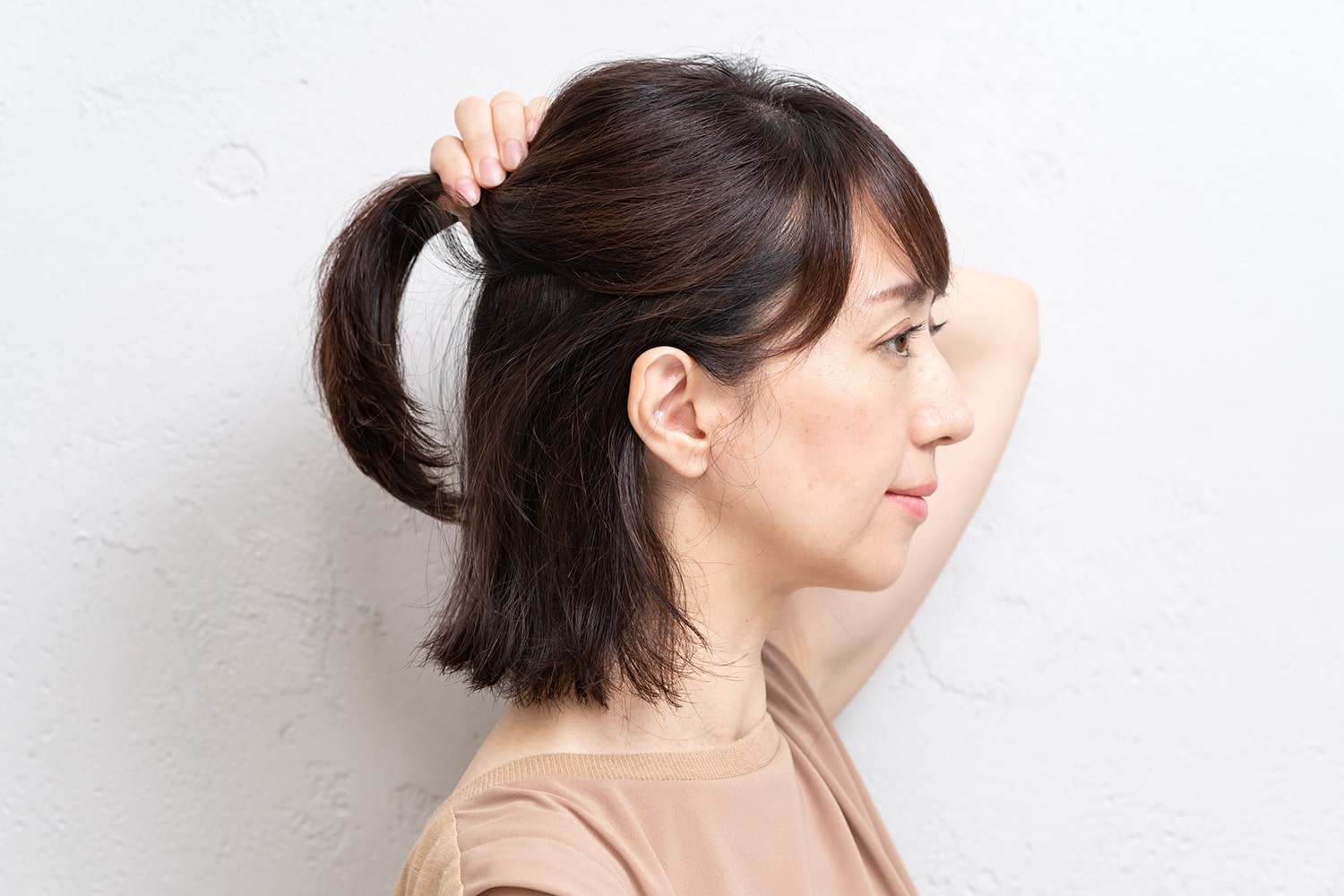 はちの下あたりの髪をひとつにまとめたら、手でしっかり束ねる。