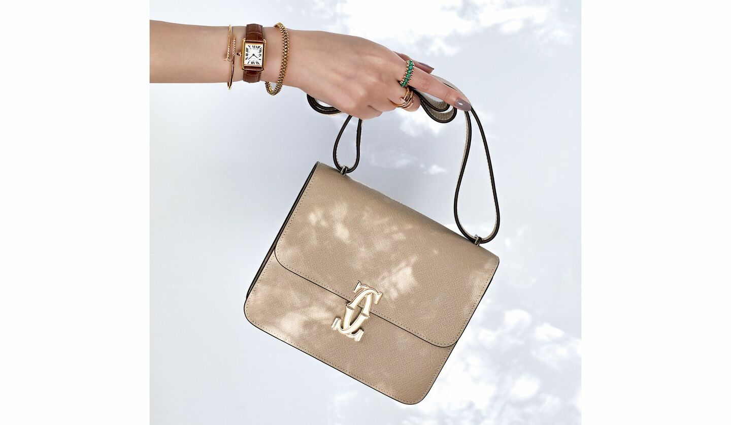 カルティエのバッグ『C ドゥ カルティエ』を持った手元。手元には指輪や時計、ブレスレット