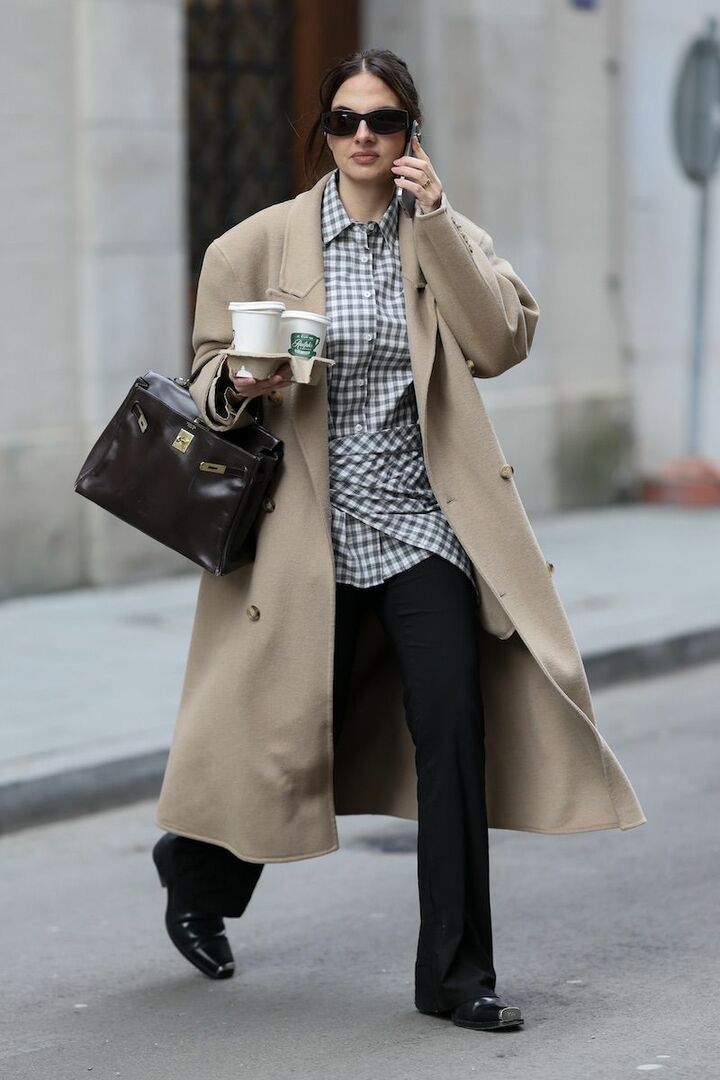 落ち感のあるパワーショルダーのベージュコートは、翻る様まで絵になる一着。