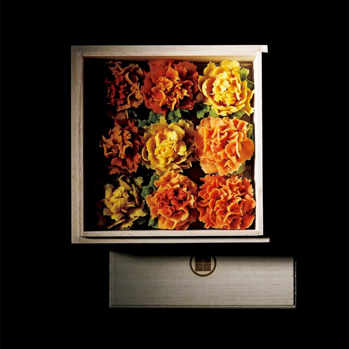 東京・桜新町にあるおはぎ専門店「タケノとおはぎ」のオーダー メイドメニュー『春まど』は、最高の手土産となる花束だ。写 真からもわかるように、一見マリーゴールドと見紛うほどの精 緻な作りと華やかな彩りが魅力の芸術的な作品となっている。 こちら、ベースは白インゲンマメを材料としたこし餡に、トウ モロコシやビーツなどの野菜パウダーとフルーツピューレを混 ぜたもの。中身には柚子や無花果などのドライフルーツをまぶ し、爽やかなフルーティさと楽しい食感がやみつきになる。オ ーダー例はインスタグラム（instagram＠harumado.jp）を参照し て相談を。『春まど』［オーダーメイドおはぎ・9 個入り］￥6,480 ～（タケノとおはぎ）※デリバリーは行っていません。