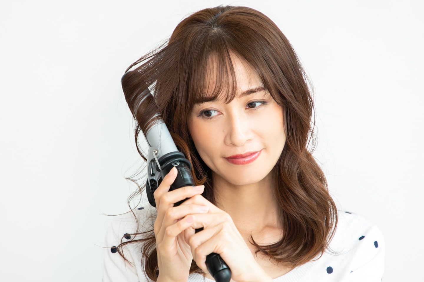 コテは32mmを使用。根本からではなく、毛束の中間を巻くイメージで。全方位巻いていく。