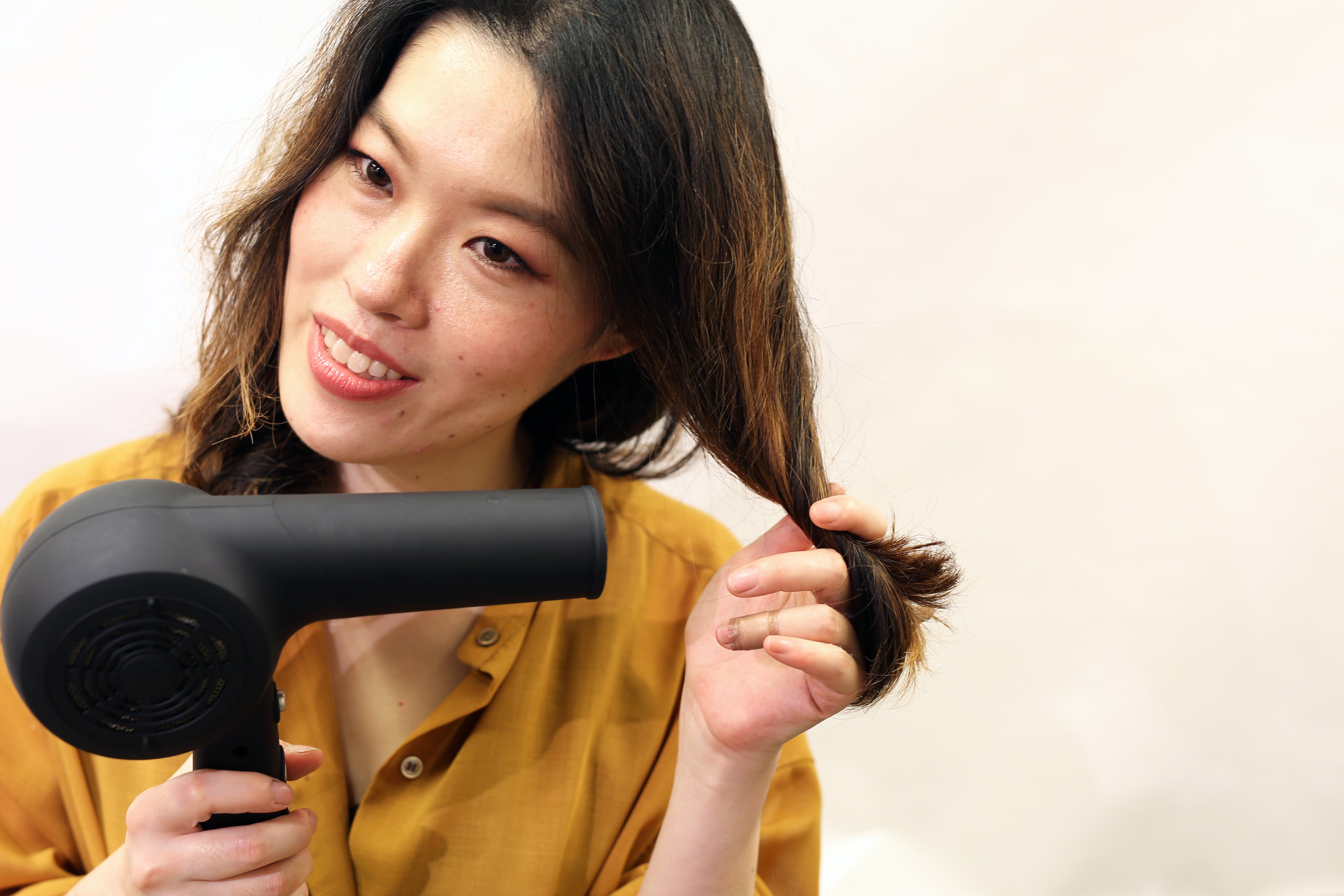 手で毛先の毛束を指に巻きつけるように乾かすとまとまりが出る。