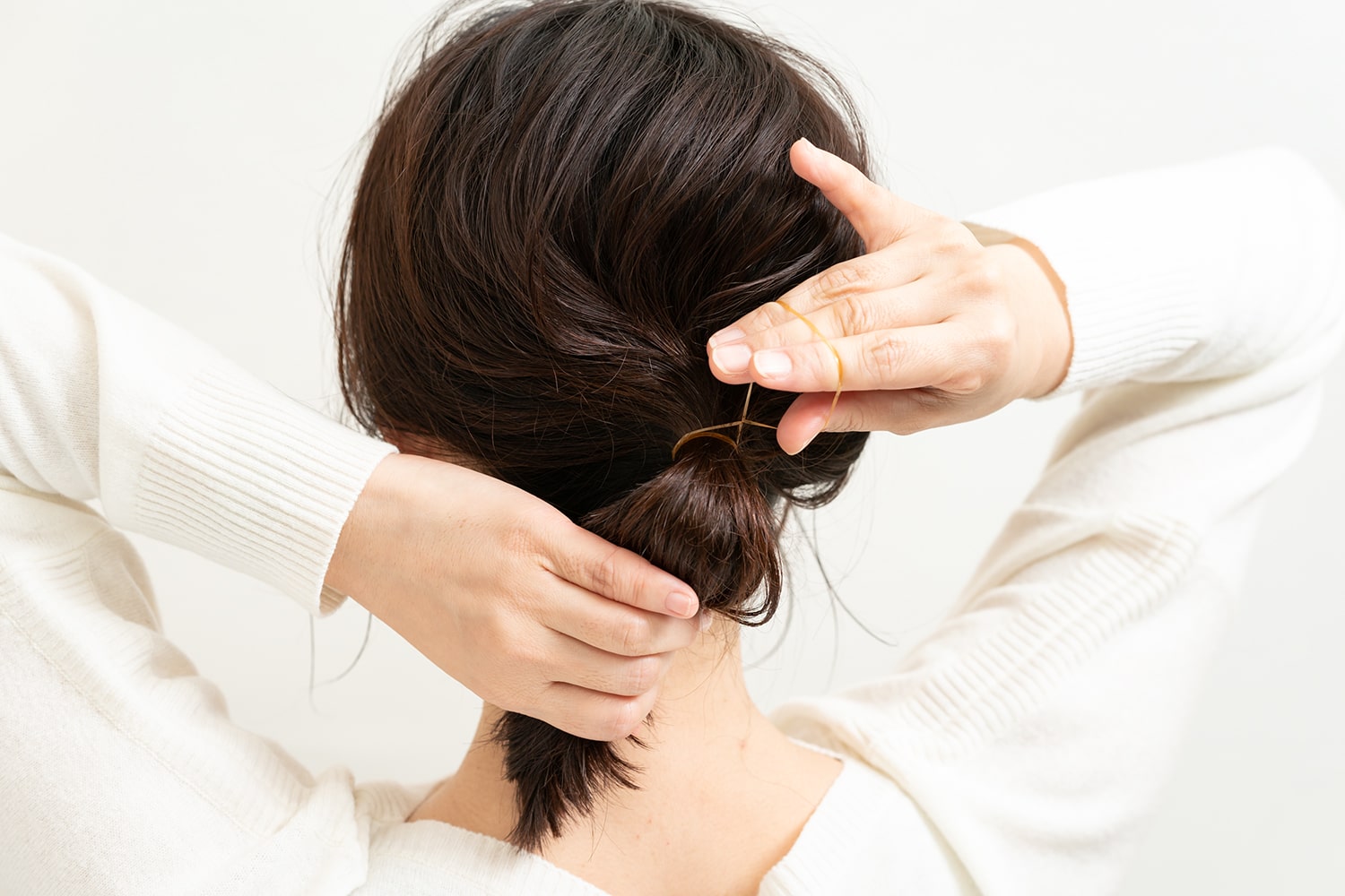 耳より上の毛束を束ねるとき、下の毛束と一緒にゴムでまとめる。