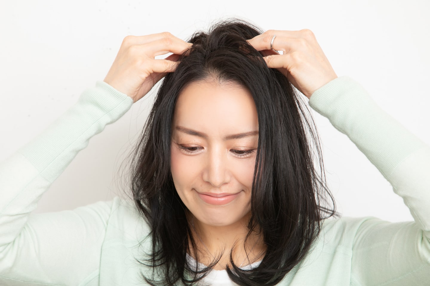 トップがふんわりするように、つむじに向かって髪を押し上げてボリュームを出す。耳周りの髪をつまみ、サイドに広げる。