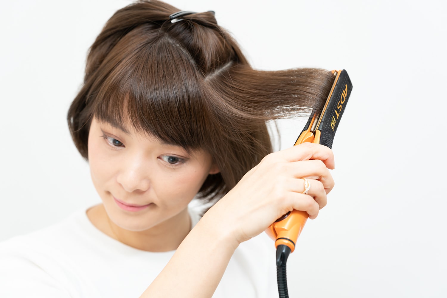 また上下にセクショニング。下段の毛束の中間から毛先にかけてストレートアイロンをすべらせたら、上段も同様に。