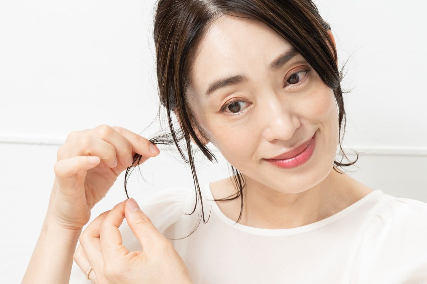 手指に残っているバームで後れ毛をつまみ、束感をつくる。