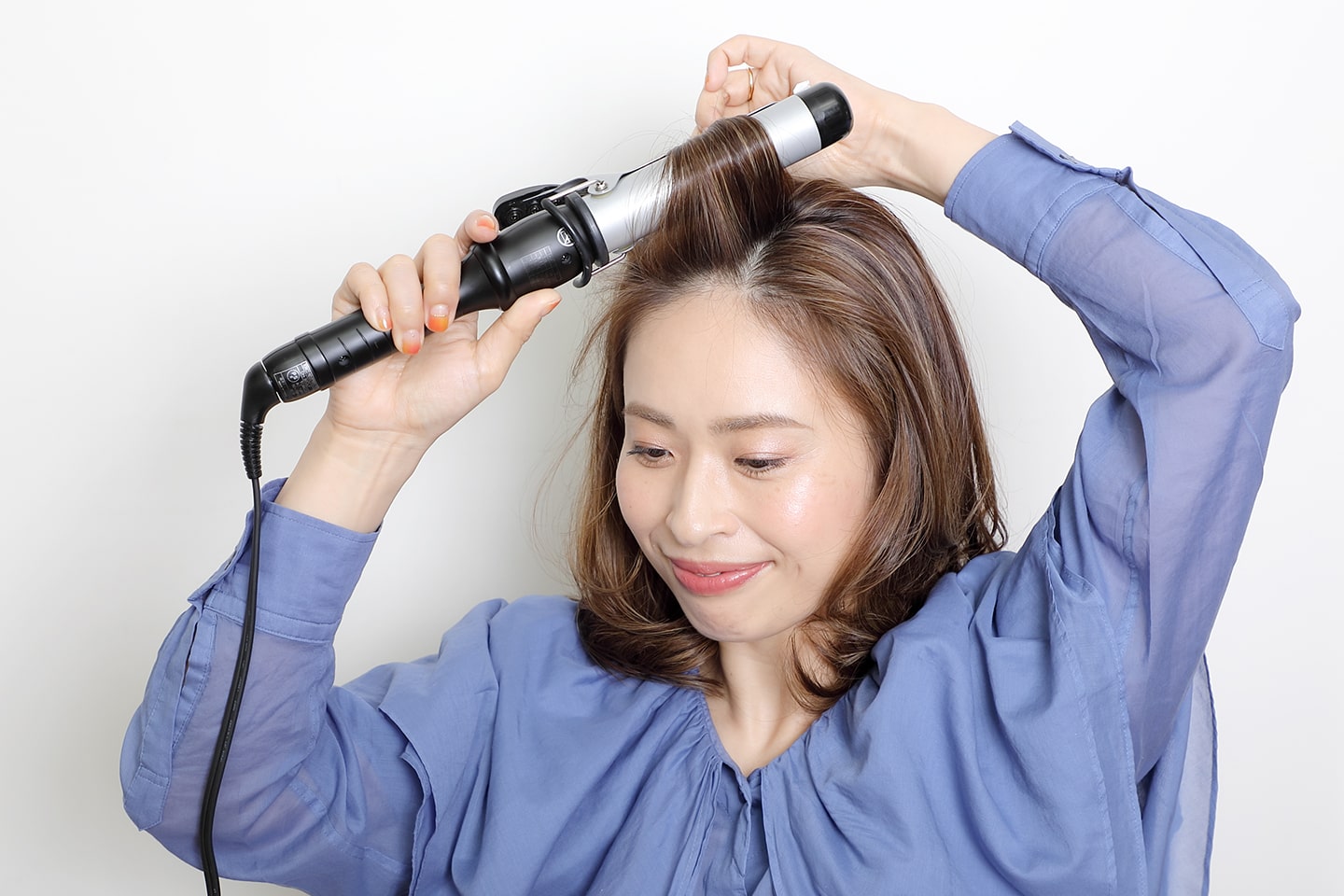 32mmのヘアアイロンを使用。ハチ上部分の根元にヘアアイロンを当て、立ち上がりをつける。