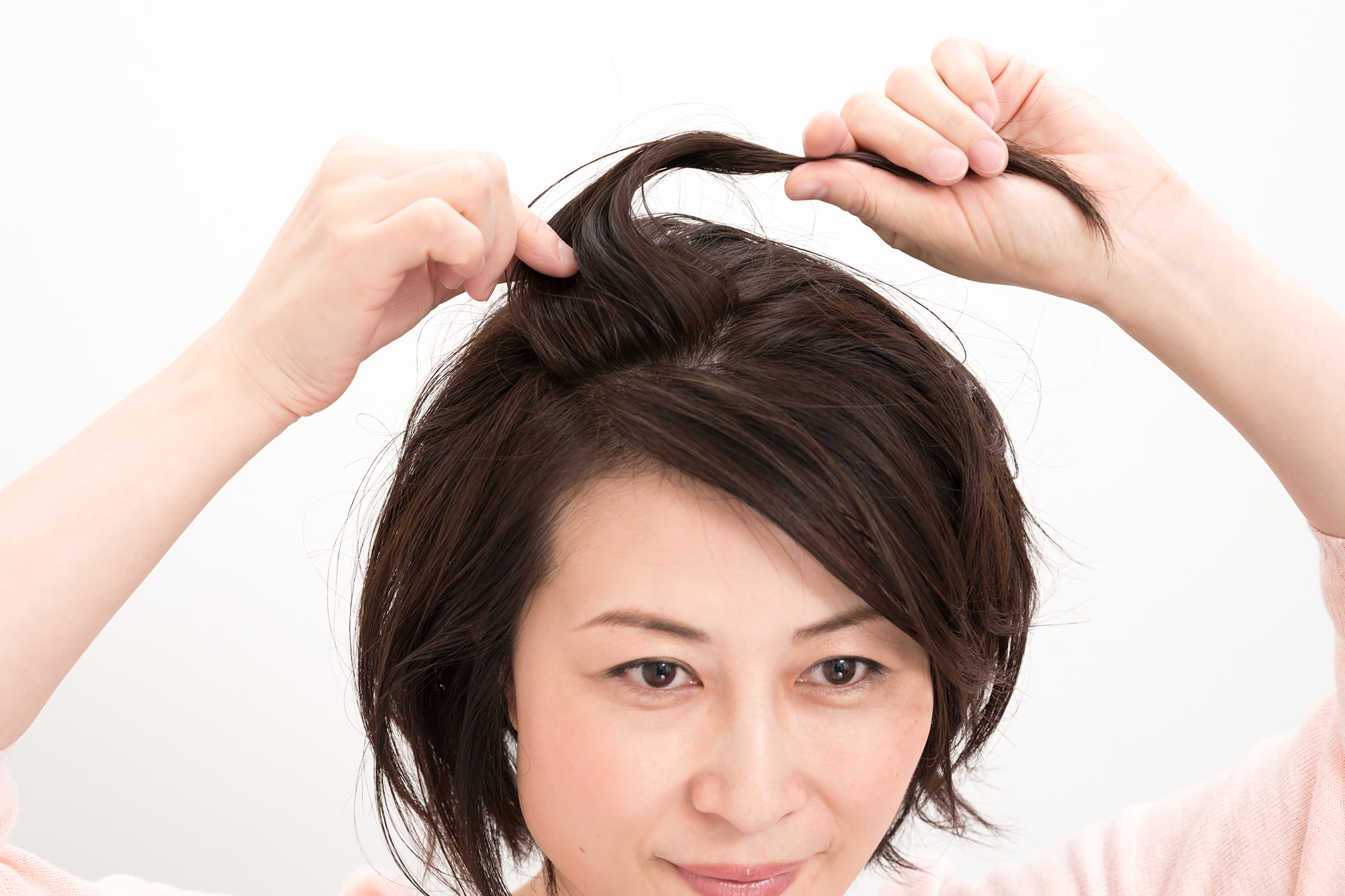 片手で毛束をつかみ、逆手で根元にワックスをなじませる