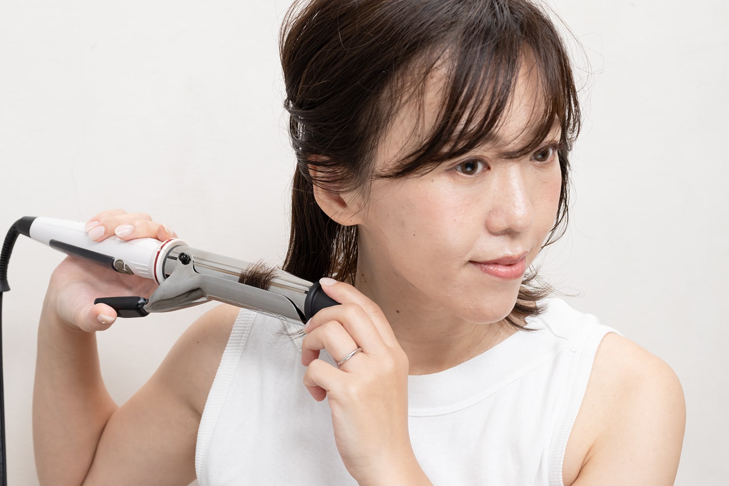 コテは32mmを使用。ランダムに毛束をとって毛先を外ハネに。耳のところで髪を上下に分けて上をまとめて置くとやりやすい。