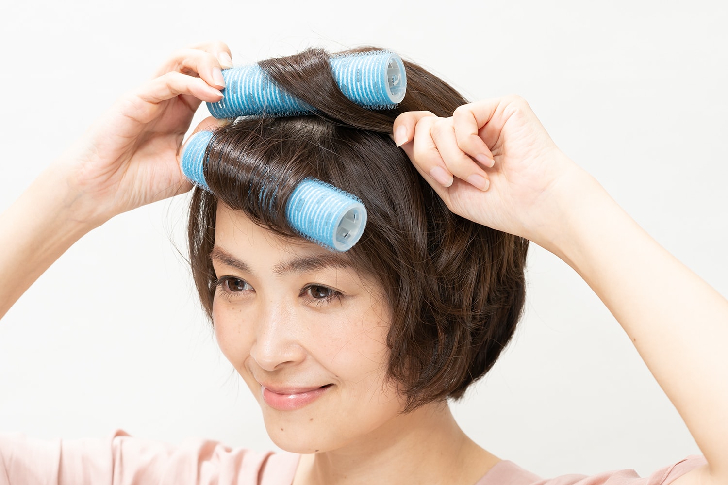 生え際の前髪から、毛先を持ってカーラーに内巻きに巻き付ける。その上の髪の同様に。
