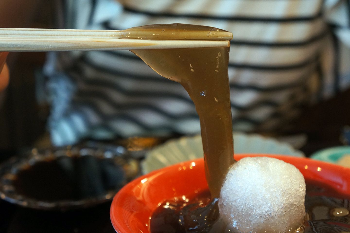箸でつまんだわらび餅がのびている画像