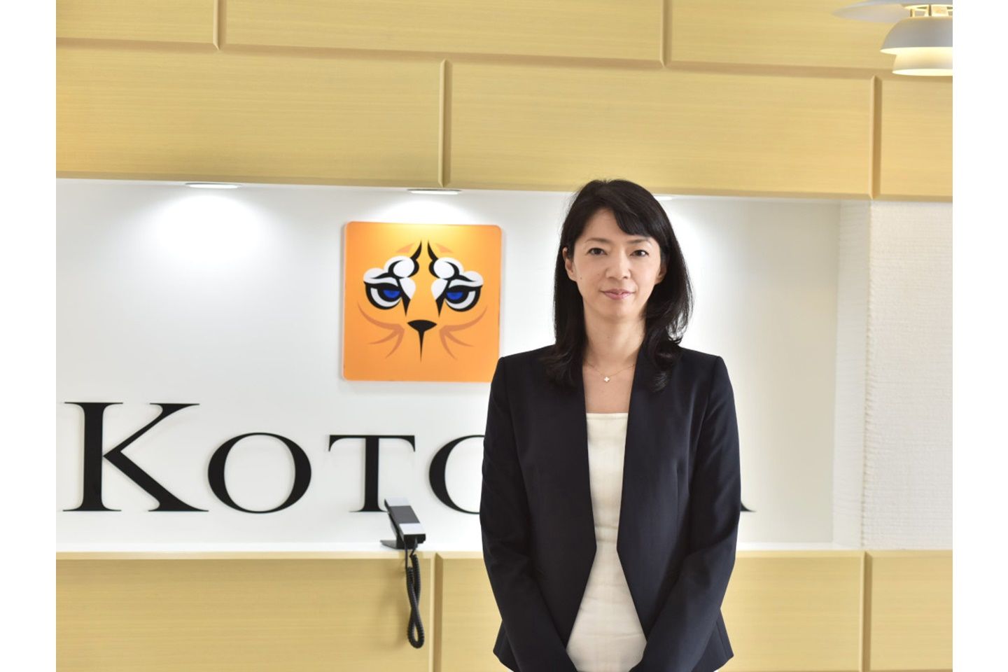 会社の看板の前で写真に写る大西利佳子さん