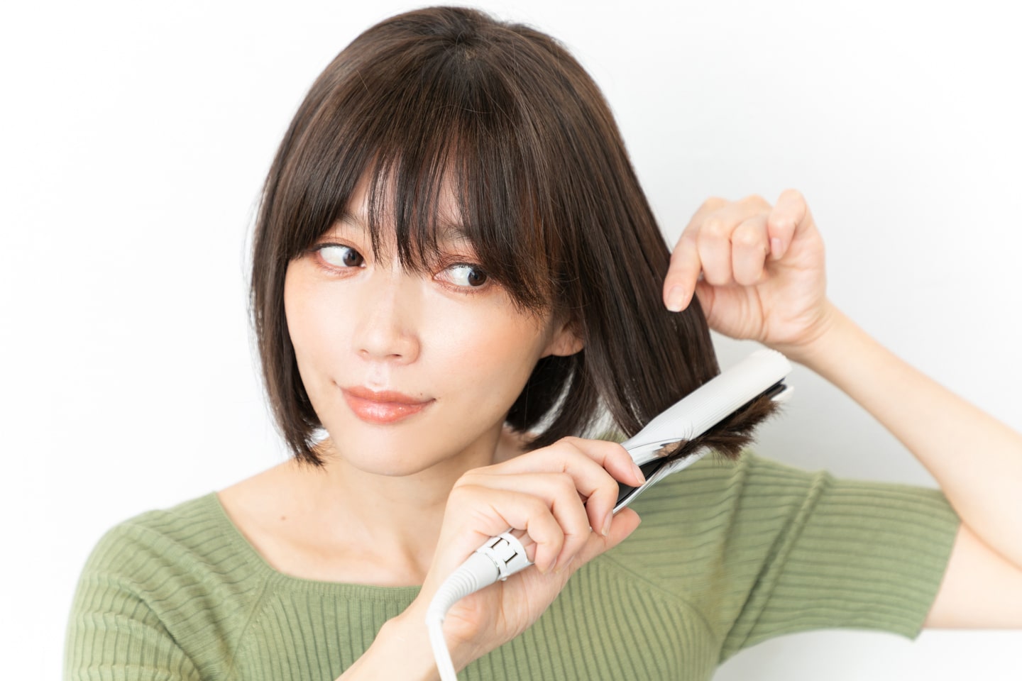 耳前、サイドの毛先をまとめて挟んで外ハネに。さっと熱を通すイメージで。