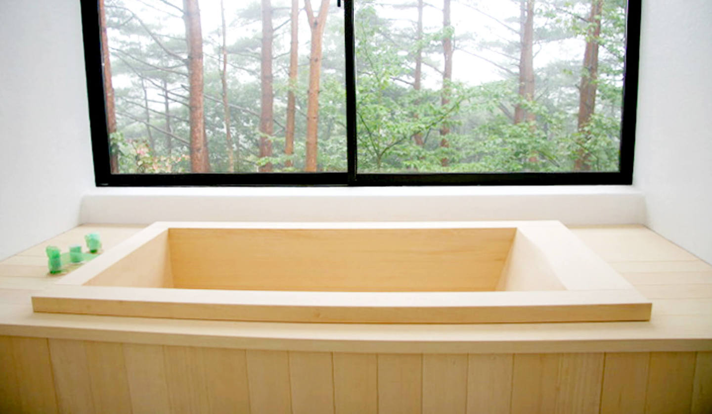 エステック アソシエイツが施工した個人宅に設置された国産のヒノキ風呂。窓の外は、森林が広がっている。