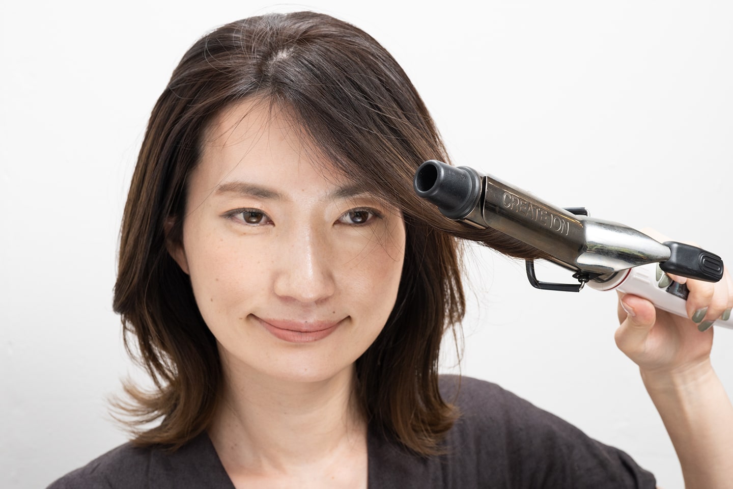 毛束を斜め前に引っ張るようにして毛先を外巻きにワンカールさせる。