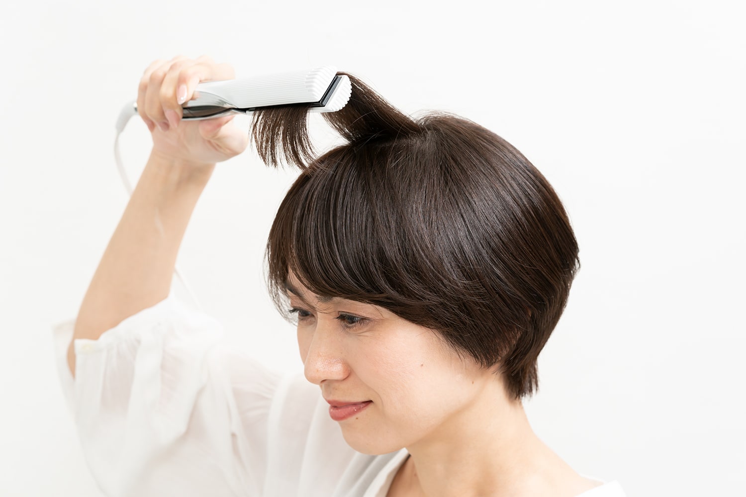 髪の根元を立ち上げるように毛束を立たせながら、毛先を内巻きにする