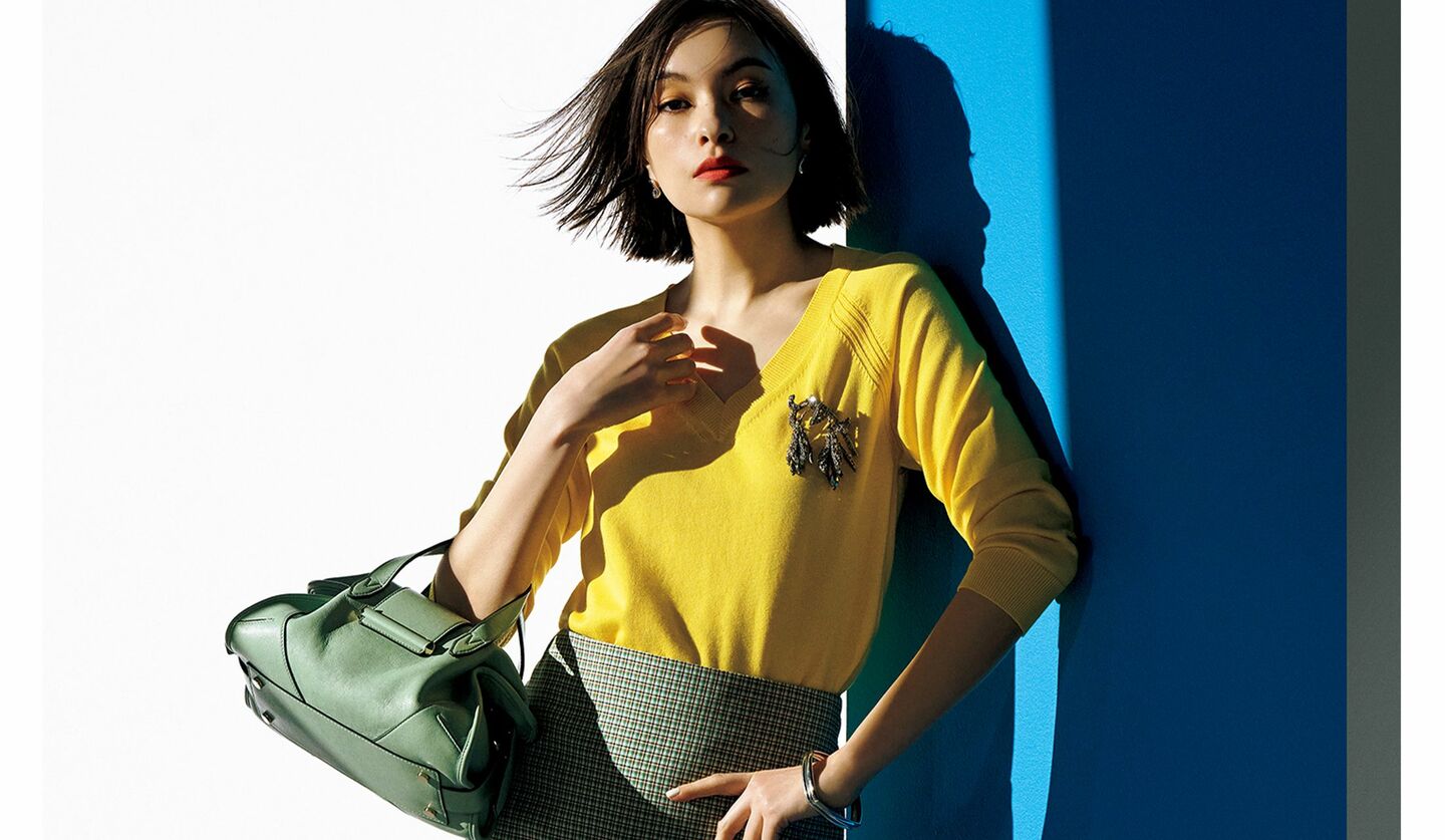 蛍光色のように目を奪うイエローのニットは、今年らしくコンパクトなシルエットとVネックの肌見せで軽やかに。「ヌメロ ヴェントゥーノ」のニットとスカート・「JIMMY CHOO」のバッグを着用した太田莉菜さん