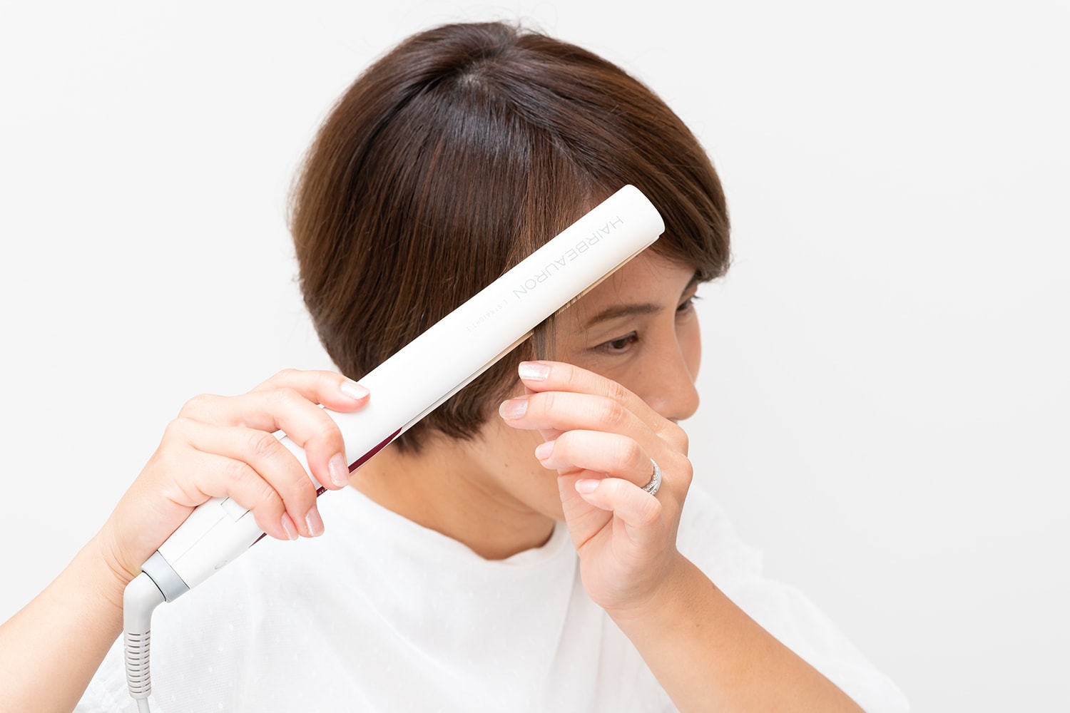 フェイスラインの髪を根元近くから真っ直ぐ伸ばしながら毛先だけ内巻きにする。
