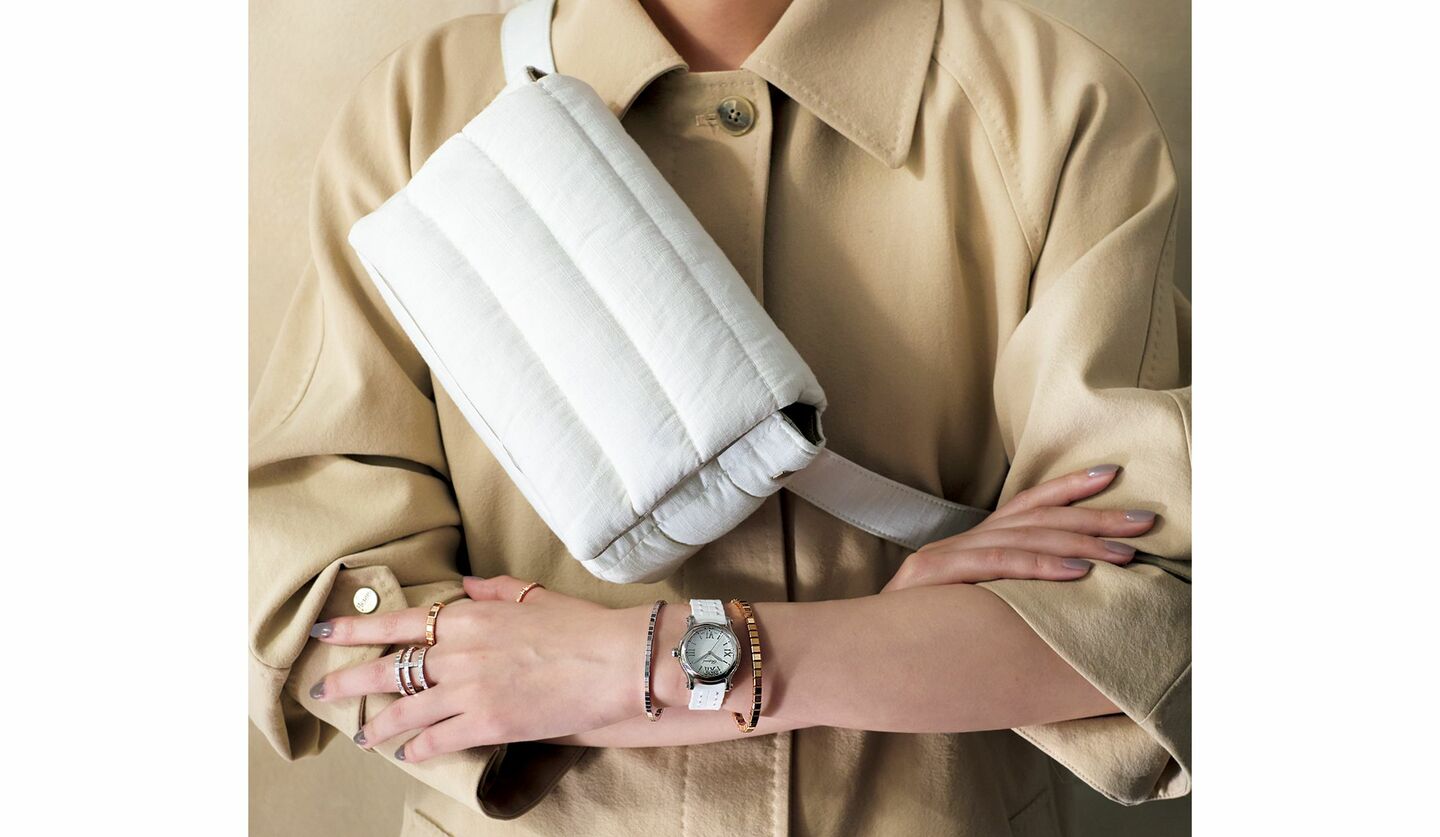 「ヘルノ」のボディバッグと「ショパール」の時計・ジュエリーを着用したモデルの上半身