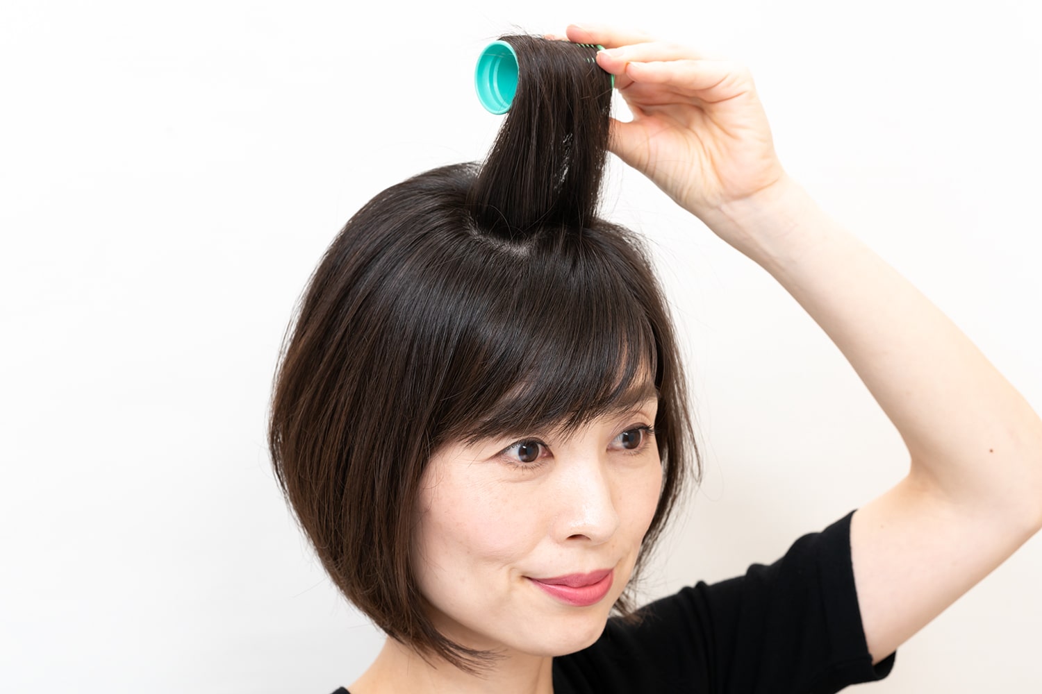 毛束の根元を立たせるように毛先を垂直に引き上げながら巻くのがポイント。このカーラーの後ろの毛束も同様にして巻く。