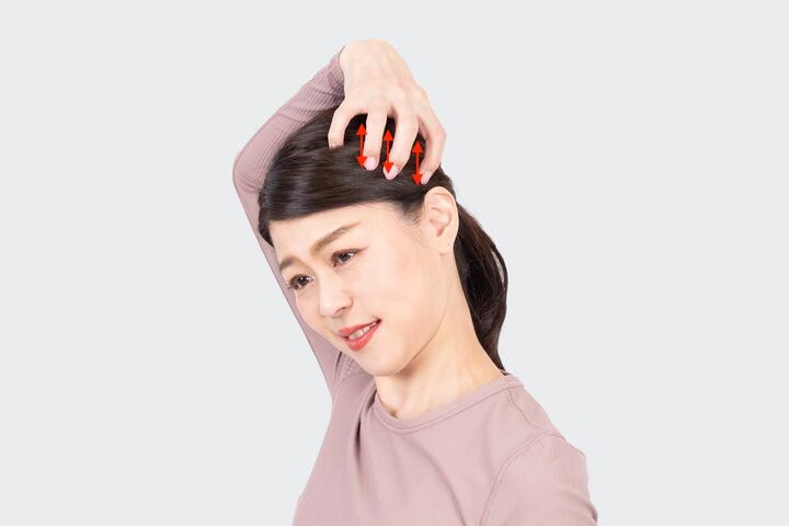 左の側頭筋を右手の4本の指でつかむようにもみほぐす