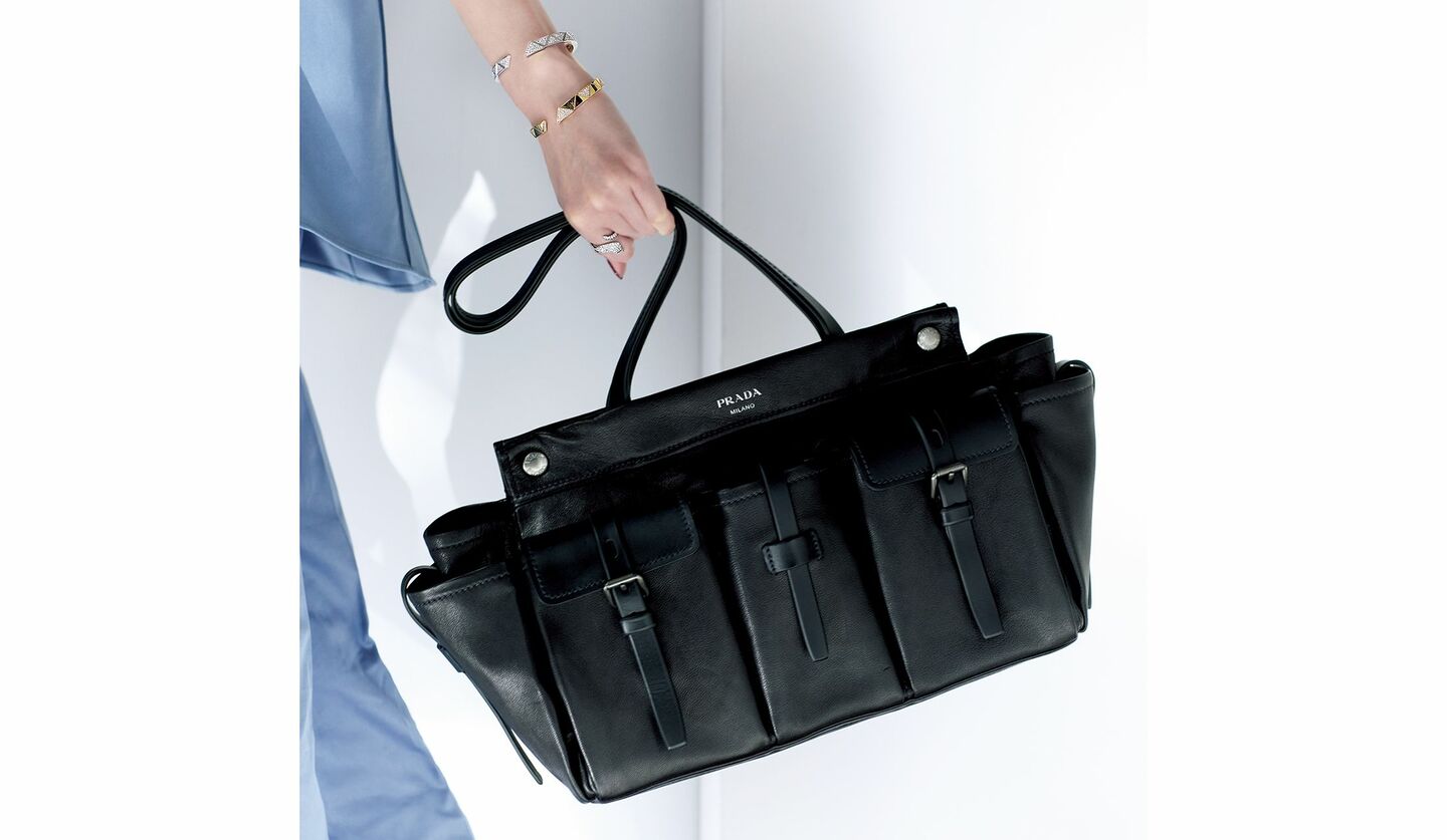 プラダのバッグを持ったモデルの手元。手元にはプラダのブレスレット2点を着用。