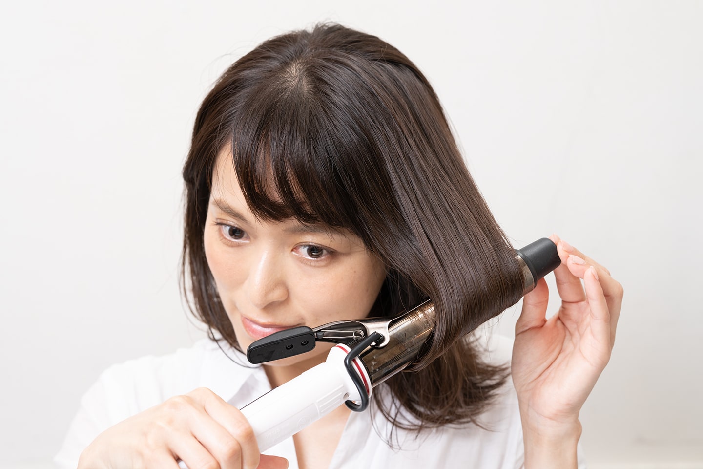 毛束の中間あたりから毛先が内巻きになるようにアイロンを滑らせる。