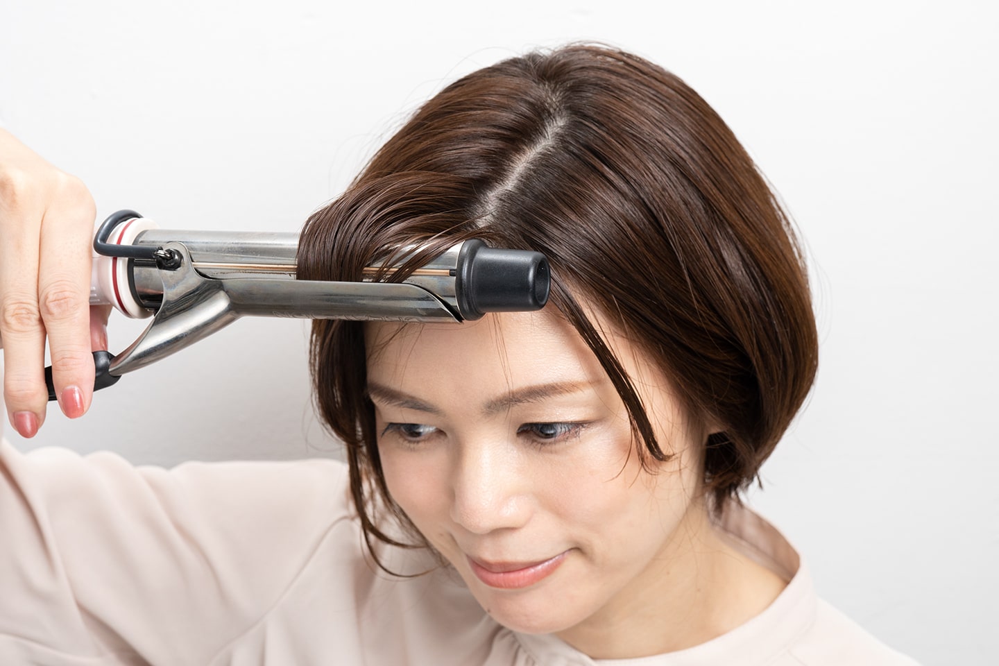 前髪を束ねて前に引っ張りながら毛先だけを内巻きに。