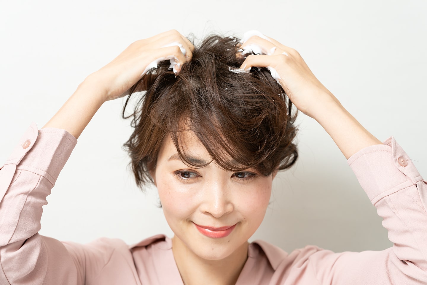 両手のひらにムースをのばしたら、下から上にとかしあげるようになじませる。