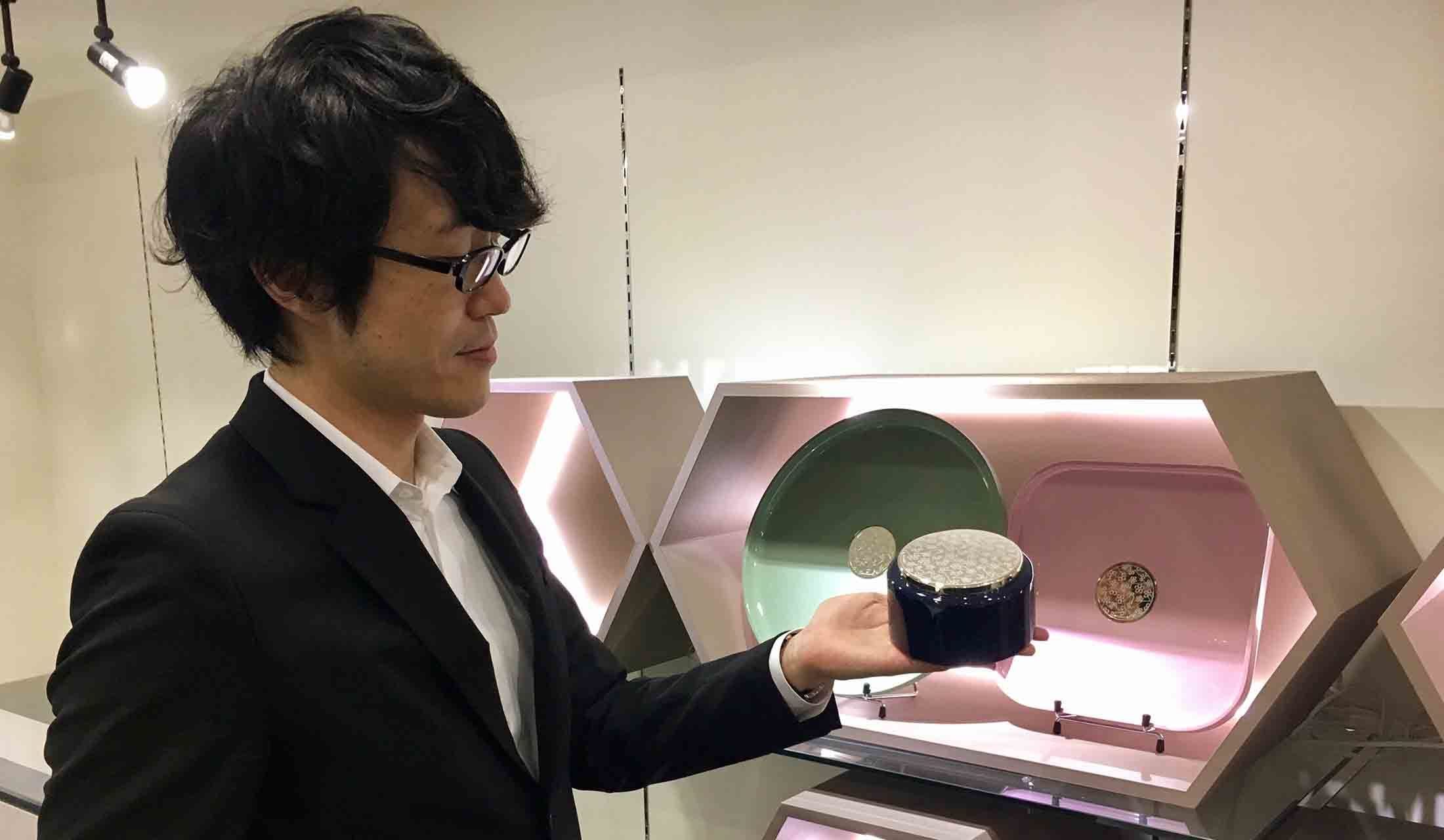 藍色の漆処理を施したウッドの筐体にシルバーが映える新作のボックスを手にする、デザイナーの佐藤オオキ氏。