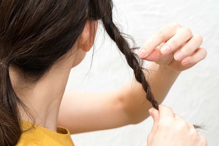ねじった髪の表面の髪をつまんで細かく引き出す。ゴムで結ぶ前に毛先から根元に向かって毛束を引き出すと引っ張りやすい。
