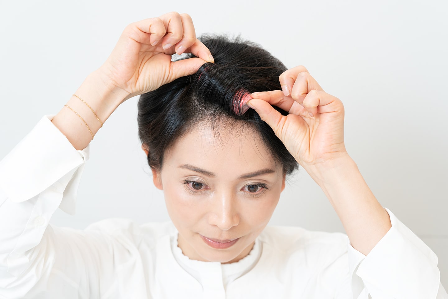 カーラーで分け目をまたぐように斜めに巻く。