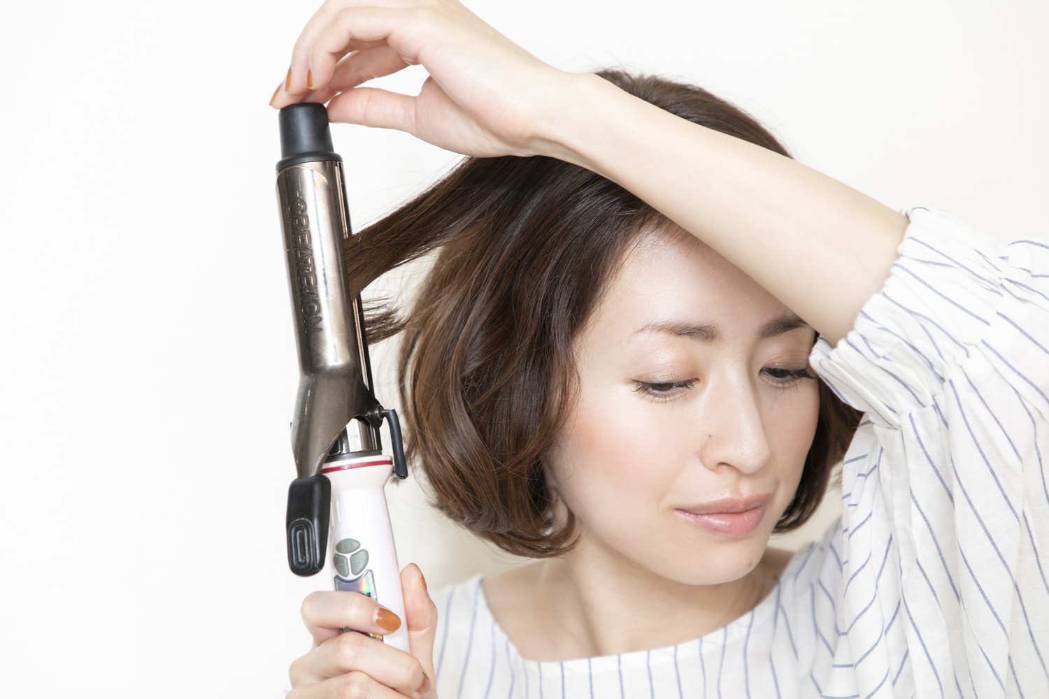 表面の髪の中間~毛先をヘアアイロンで巻く。顔の近くから外巻き、内巻き、外巻きの順にミックス巻きに。