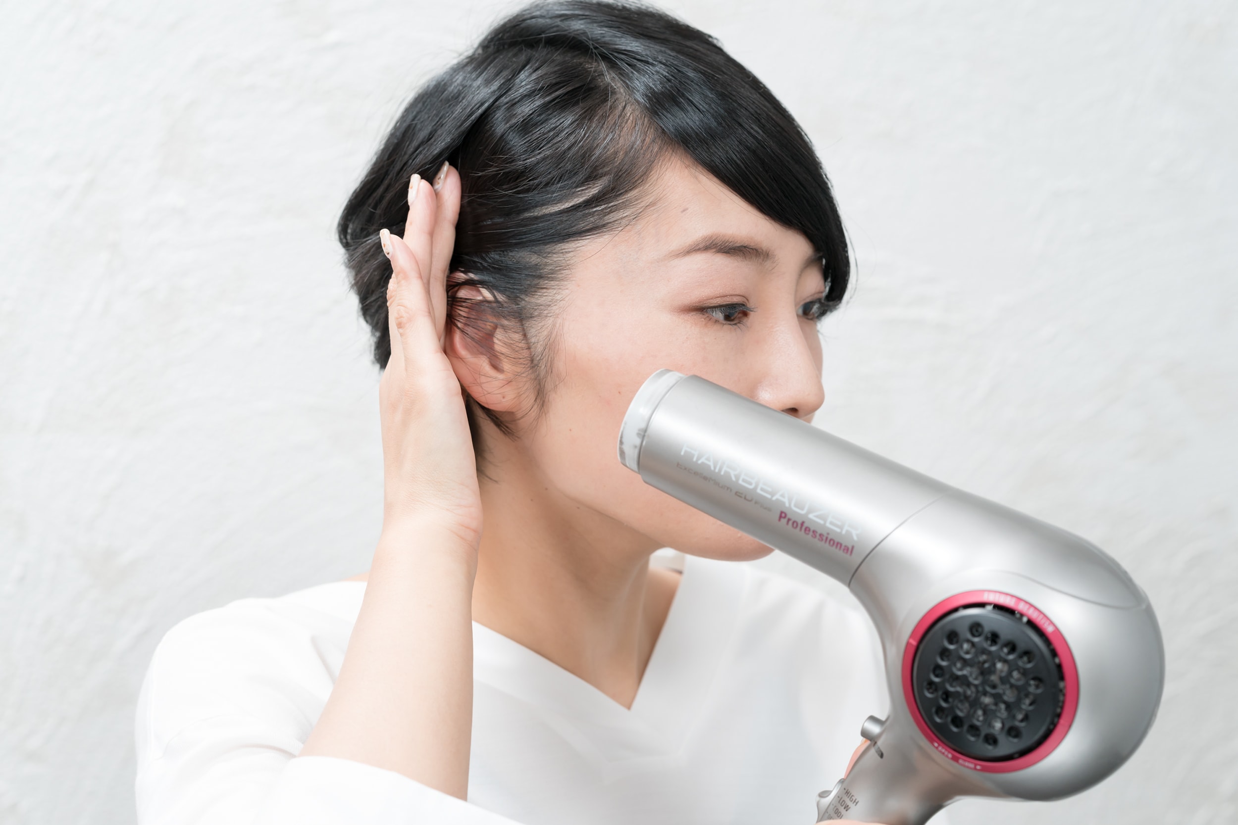 仕上げに耳上、こめかみの髪を後ろに引っ張りながら熱風を当てる。逆サイドも同様に。