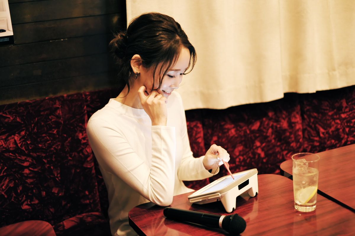 「何を歌おうかな」と曲をチェックする冨樫さん