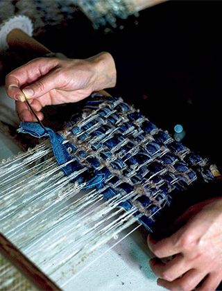 繊細な意匠糸やリボンは、機械を止めて、丁寧な手作業でフラットに織り込んでいきます。