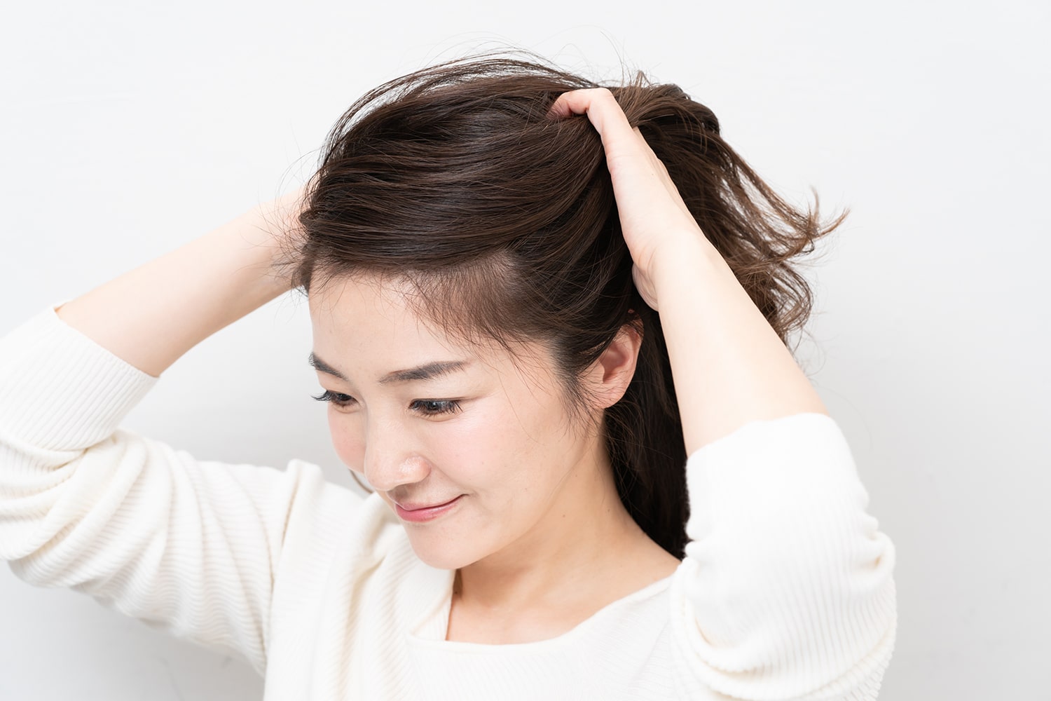 両手のひらにヘアバターを広げて髪になじませたら、形を整える。