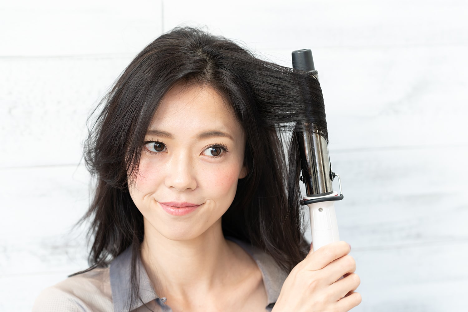 耳前の毛束を32mmのアイロンで外巻きに。華やかさが出るように毛束の中間を巻くのがコツ。
