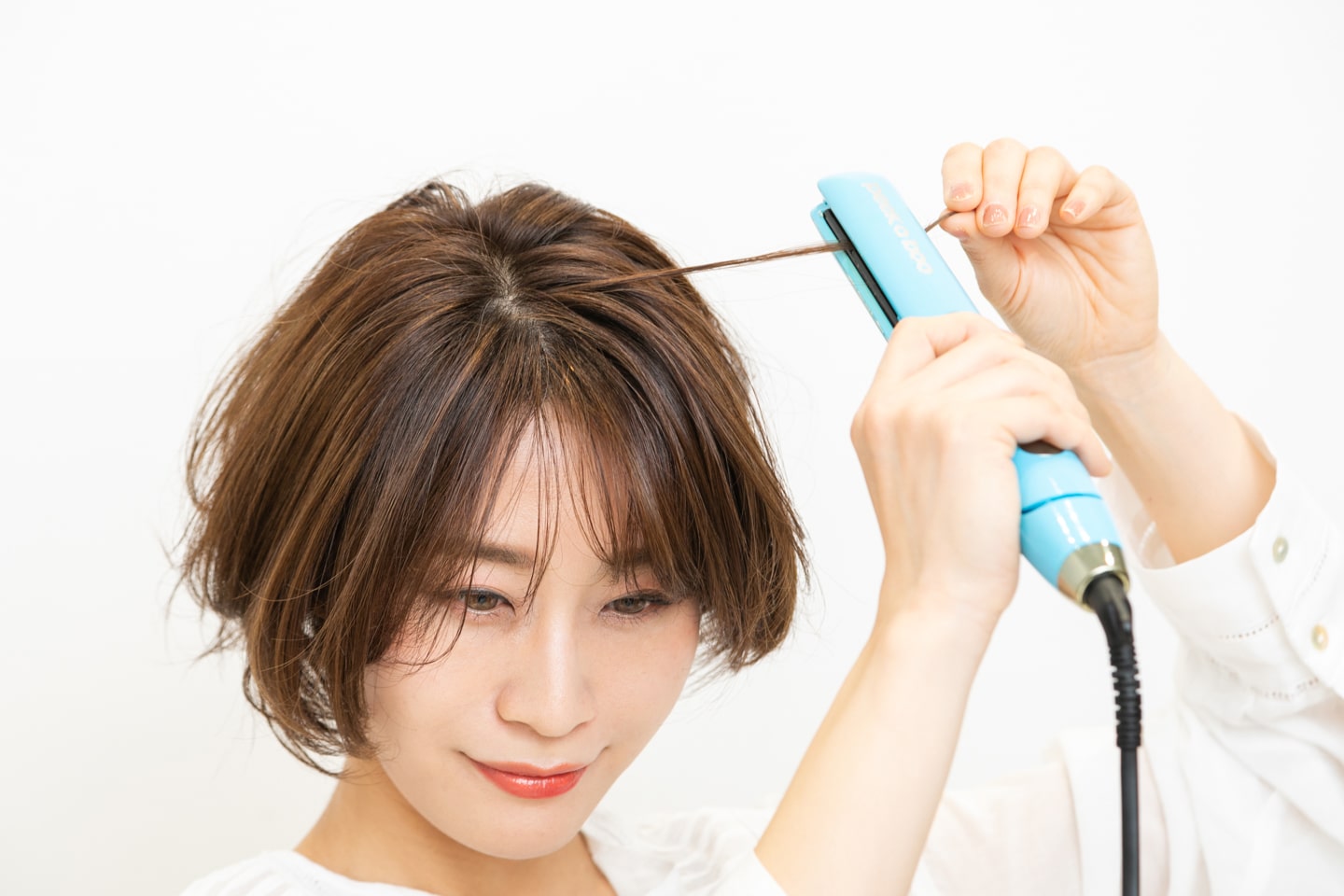 表面から細い毛束を取り、毛先が外巻きになるようにストレートアイロンを当てる。