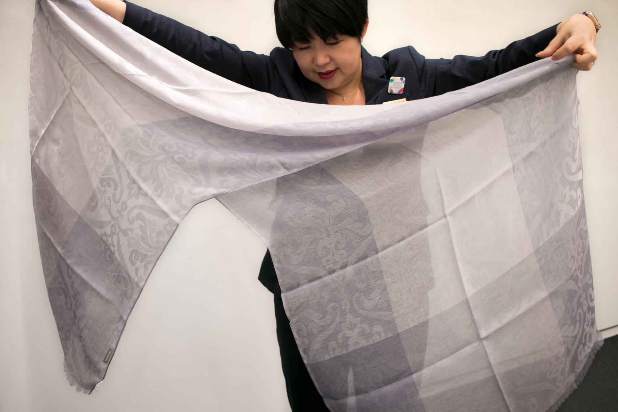 ストールの両脇を対角に1/3くらいのところを持って、中心から二等辺三角形ができるように折ります