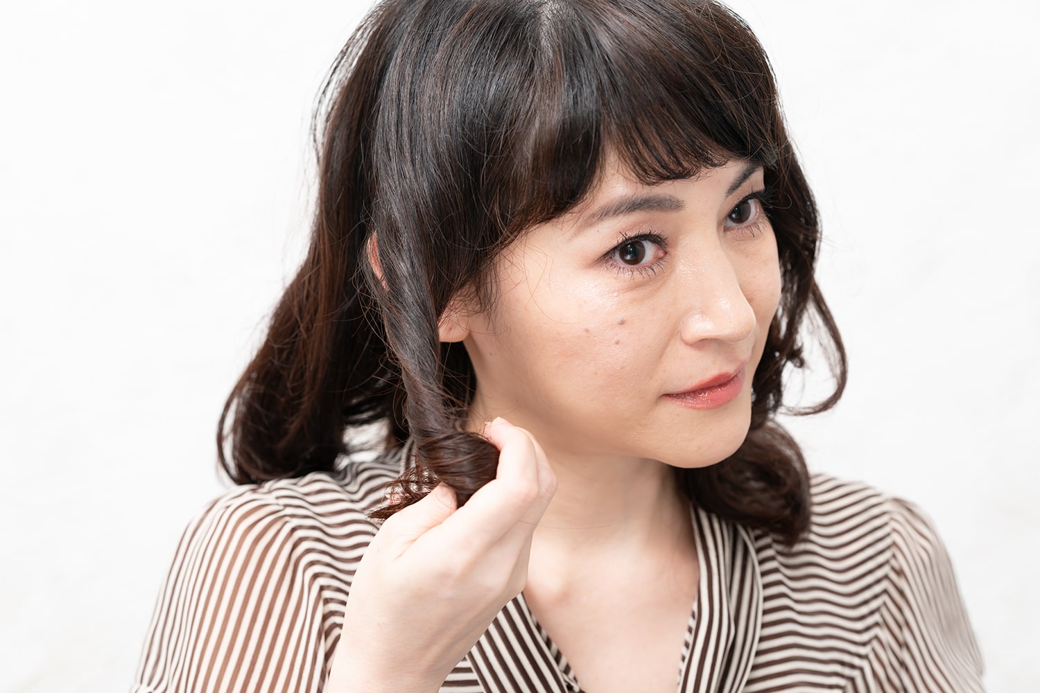 耳前の毛束を前方向にねじって握る。