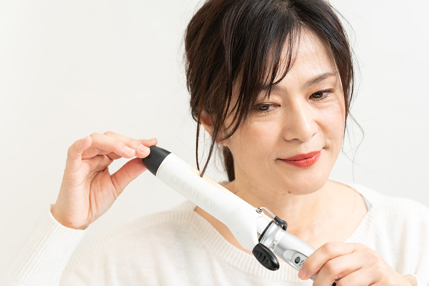 毛束をひとつまみずつ、カールアイロンで内巻きにする。