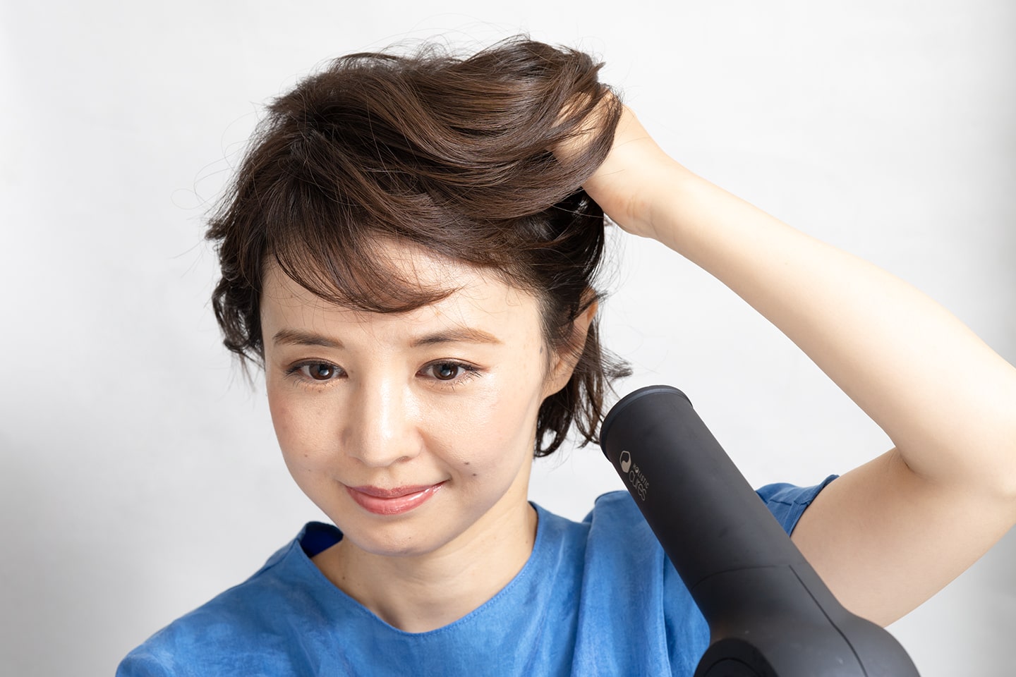 髪の根元にドライヤーをあてながら手ぐしで後ろにとかすこと。
