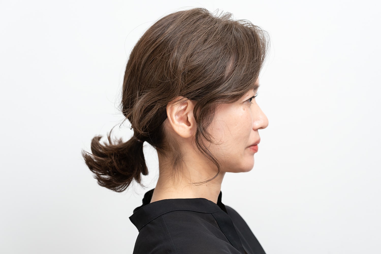 もみあげを引き出したら、髪をひとまとめにして、なるべく低い位置でゴムで結ぶ。