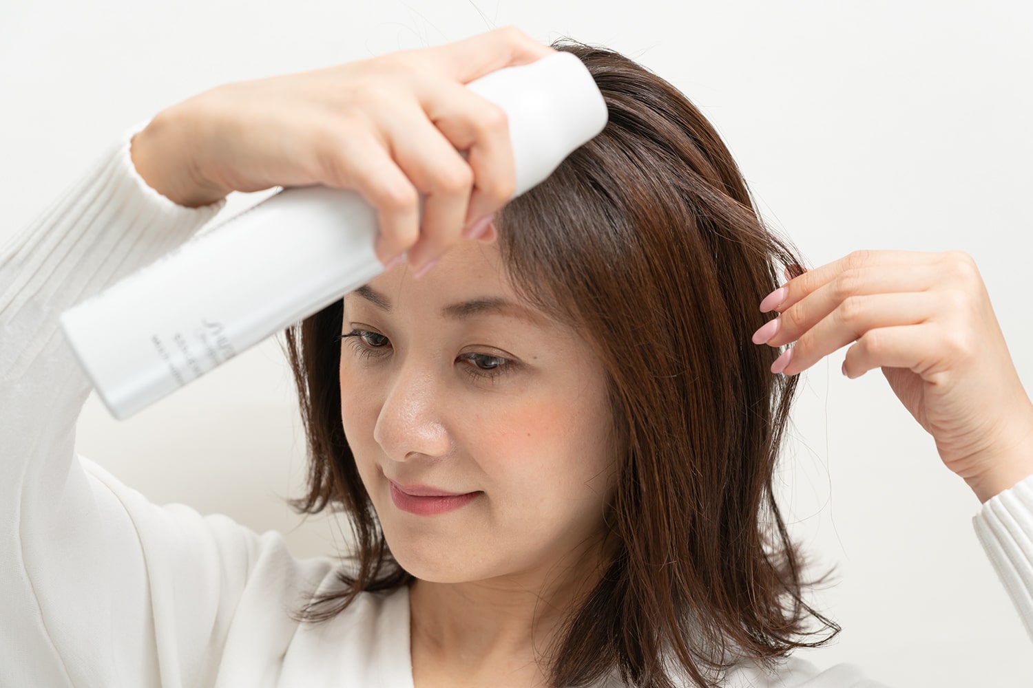 ひとつまみの毛束を浮き上がらせ、毛束の中間あたりにセット力のあるスタイリング剤をスプレー。