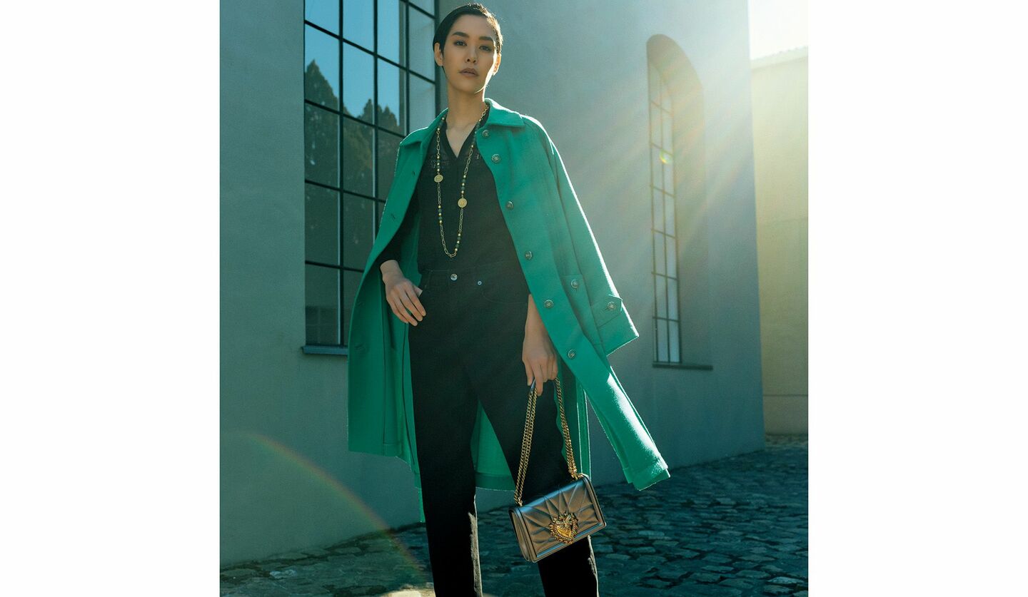 ドルチェ＆ガッバーナのグリーンのコートとブラックデニムとを着こなした女性の写真